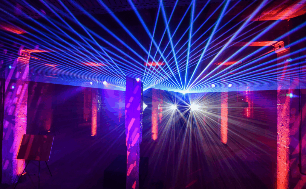 0s nostalgia inspired Christmas party in a warehouse with lasers, retro décor, and entertainment by an expert Christmas party planner.