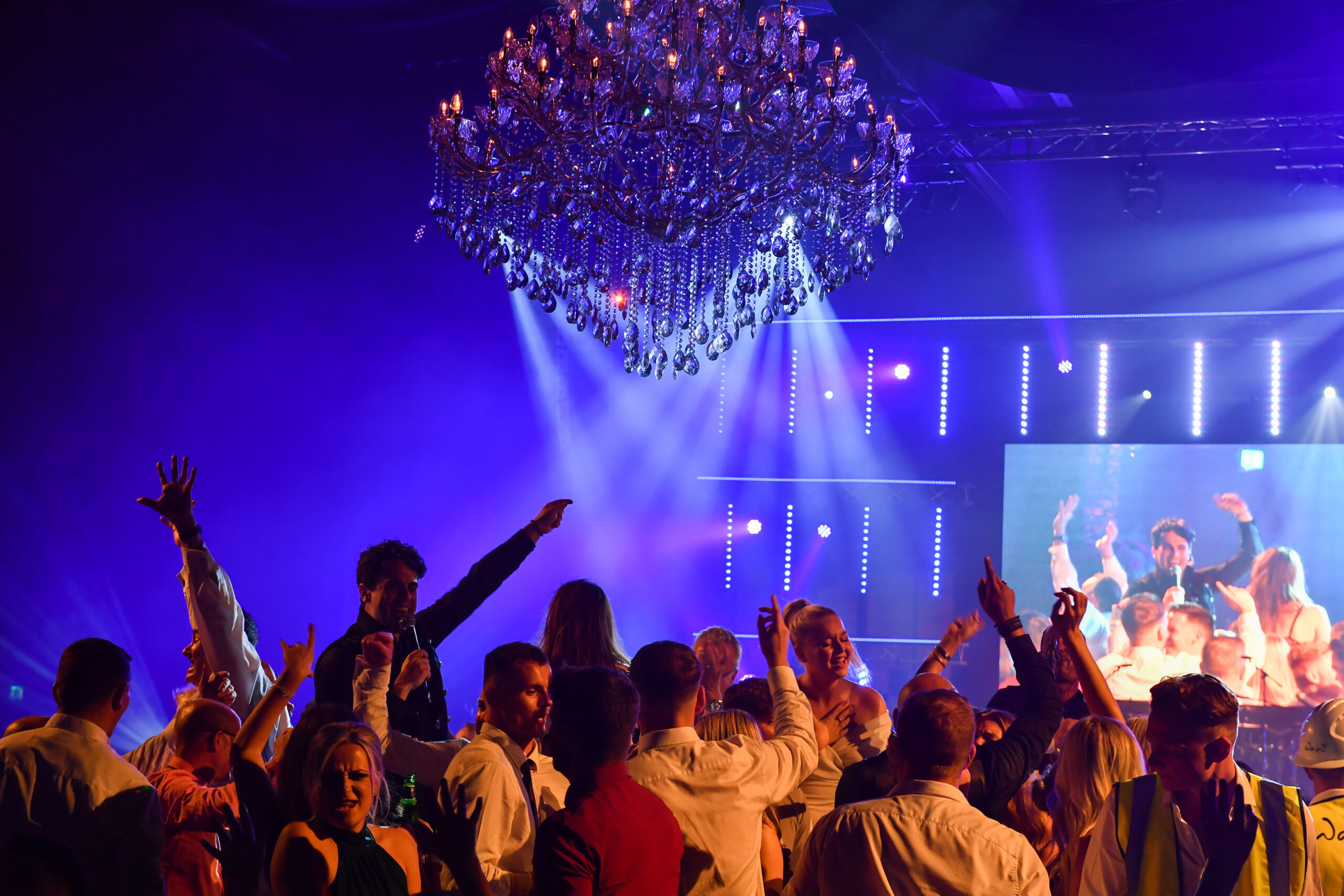 Guests dancing at a Taylor Lynn Corporation corporate Christmas party with live entertainment and dramatic event lighting.